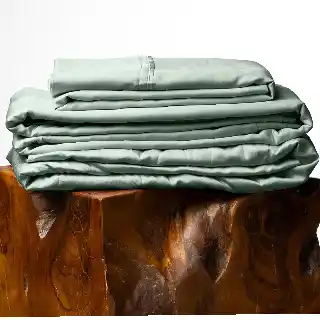 Olive Crate Tencel Lyocell eucalyptus queen size cooling sheet set in spring sage color folded on wooden stool best bed sheet for hot sleepers
